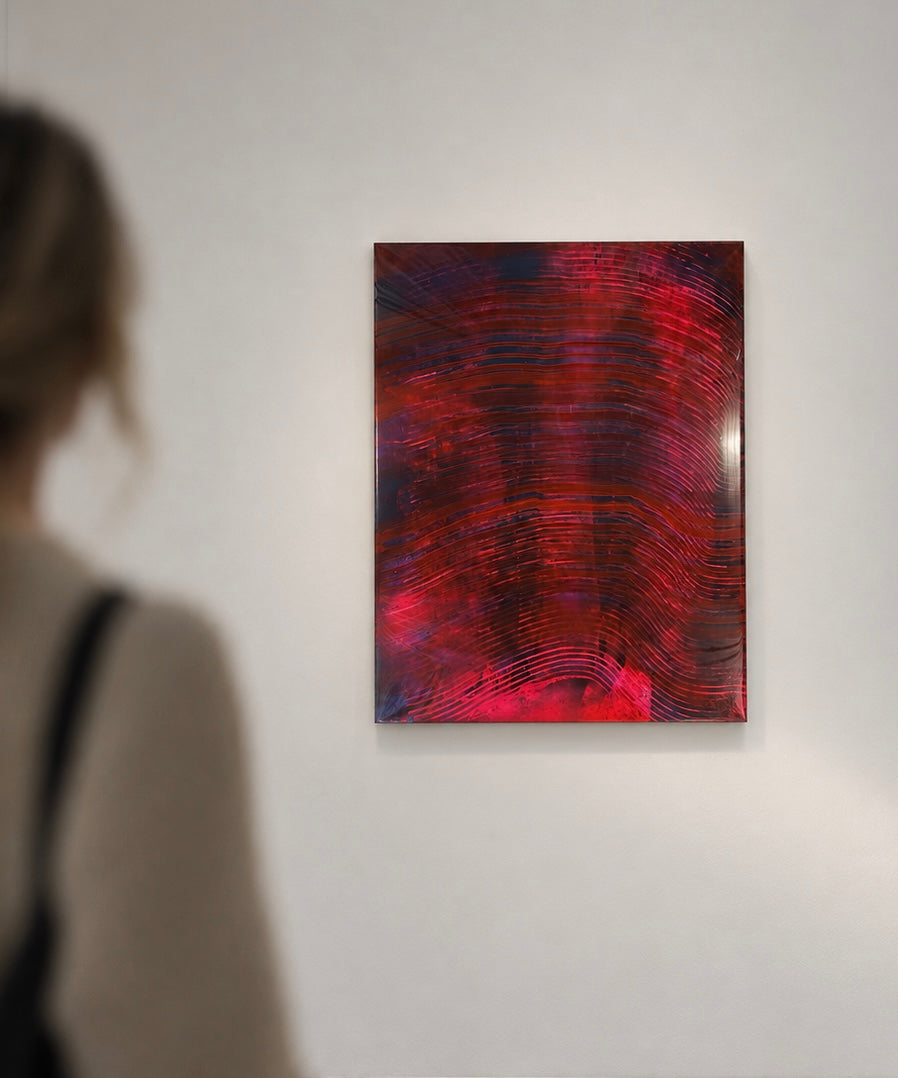 An abstract rectangular painting with swirling red, magenta, and dark blue-black brushstrokes hanging on a white gallery wall, with a blurred person in the foreground facing it.